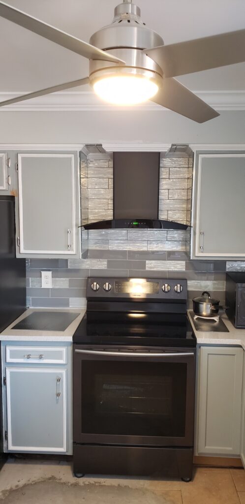 Modern kitchen stove with stainless steel hood and white cabinets.