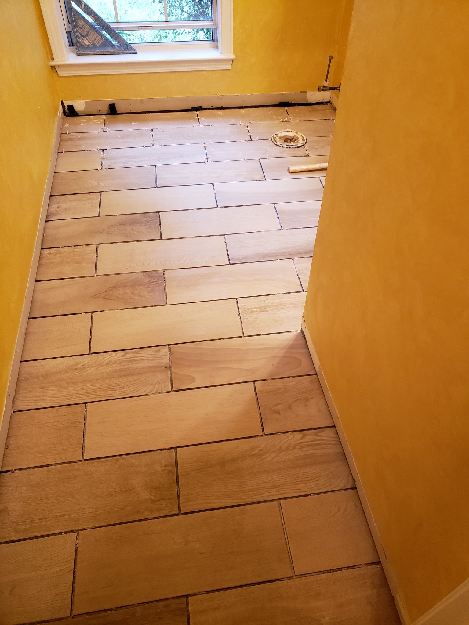 Wooden floor tiles in a narrow hallway with yellow walls.