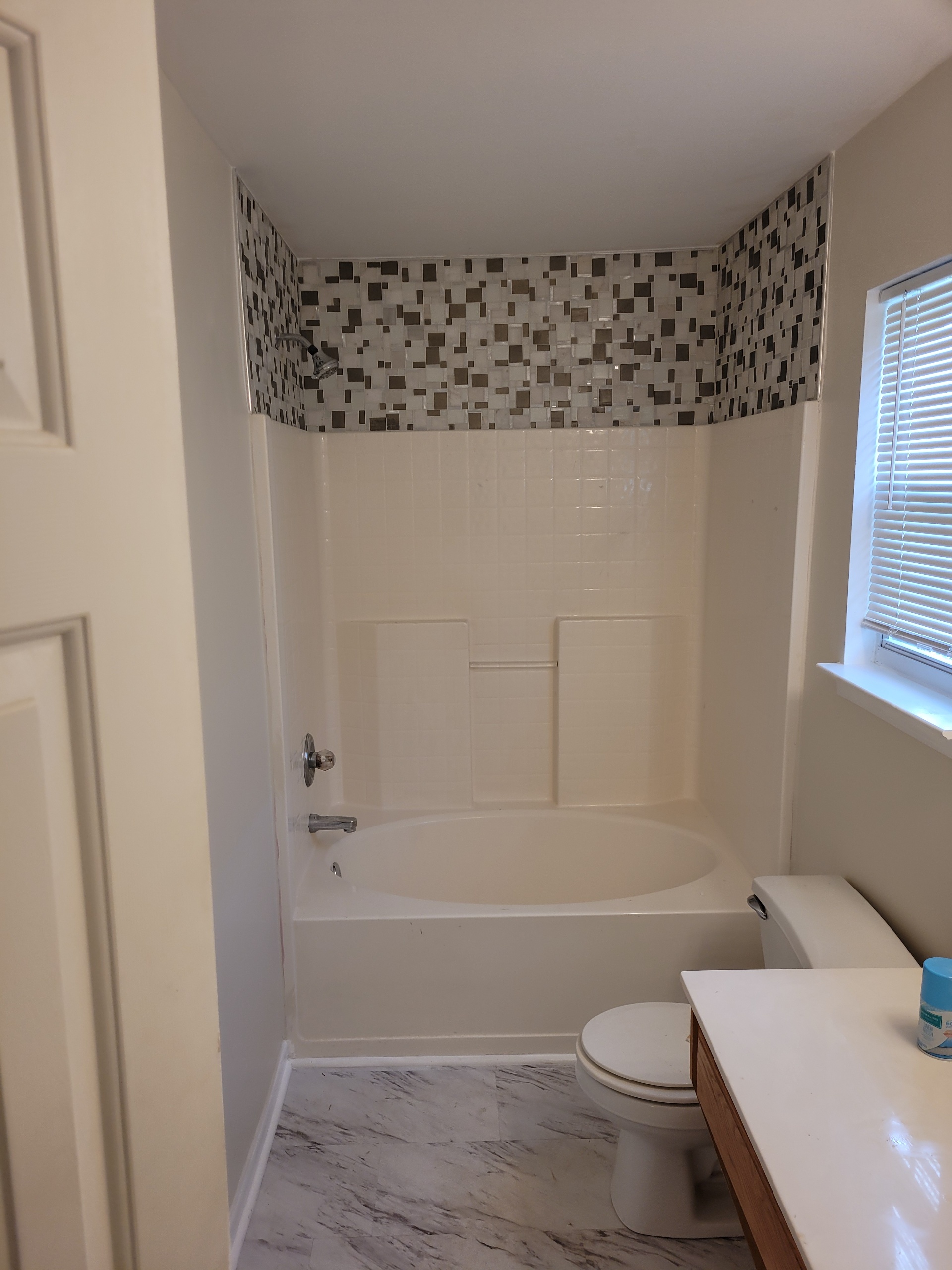 Clean bathroom with white bathtub, toilet, and window.