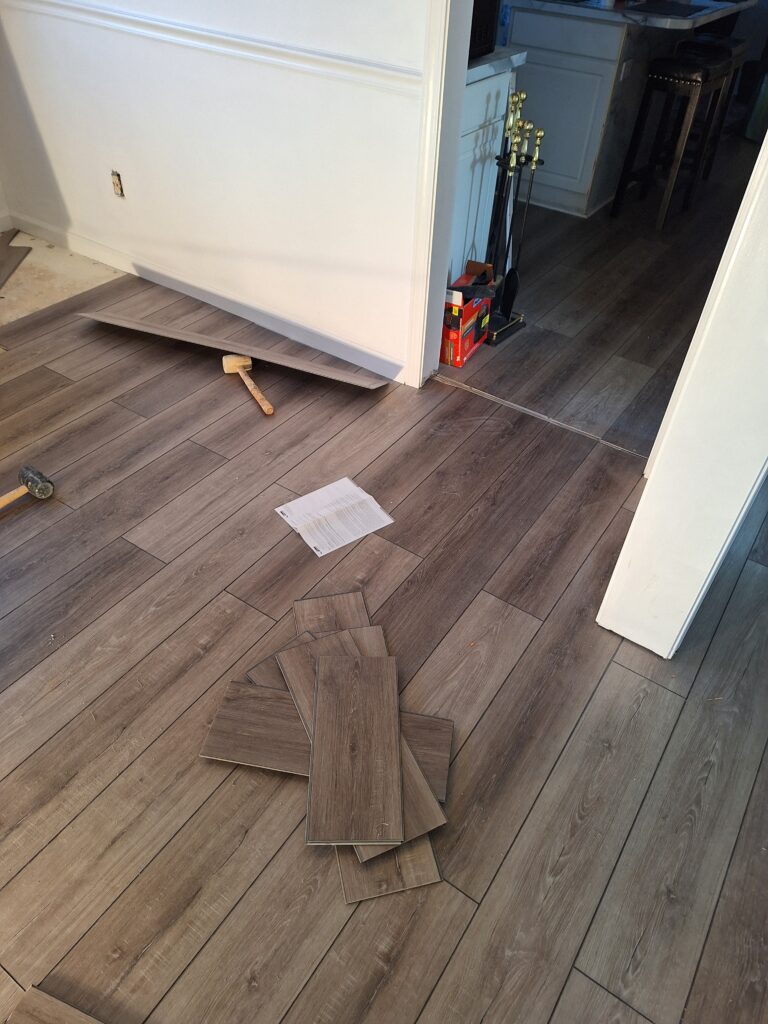 Wooden floor panels scattered near a doorway during installation.