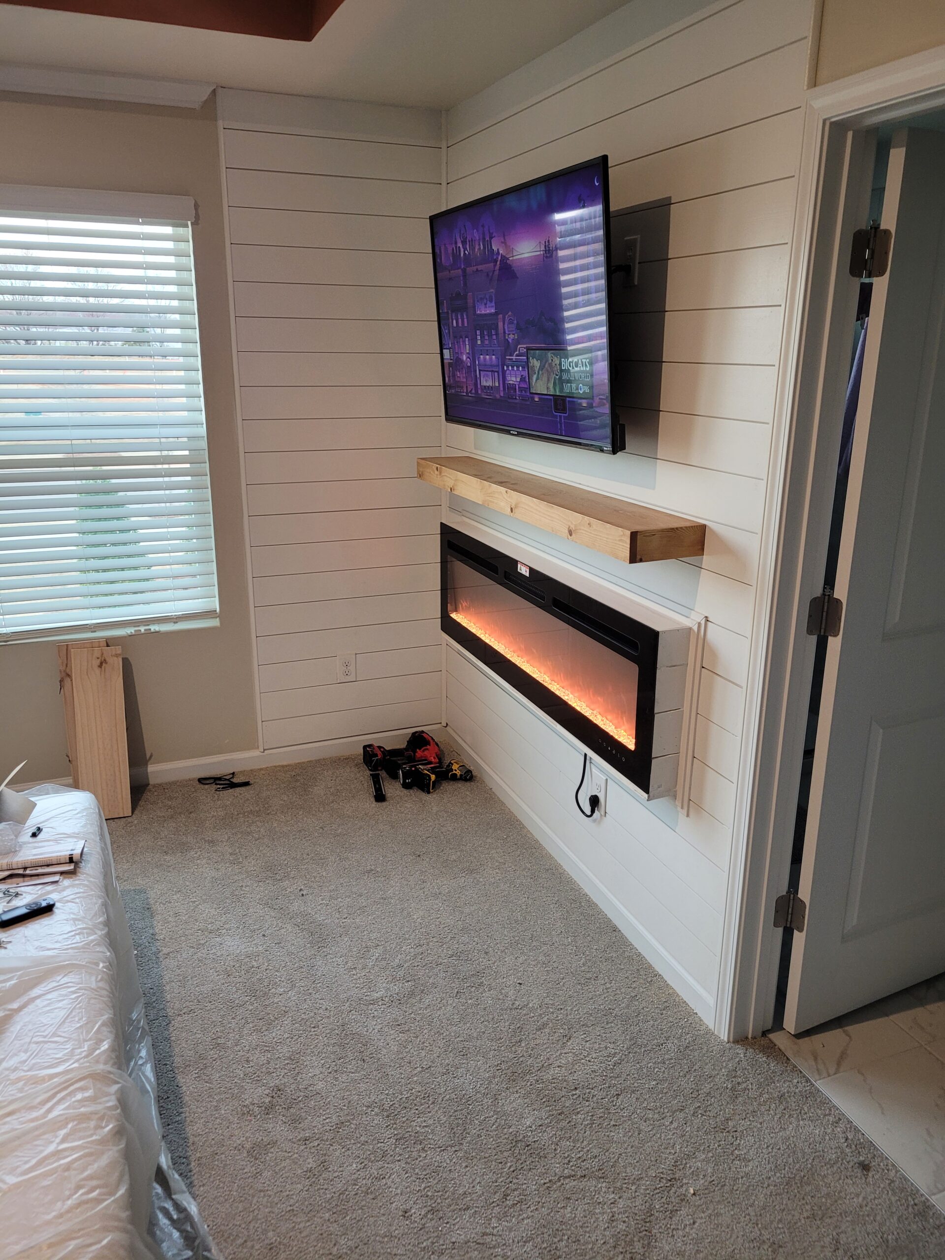 Modern living room with wall-mounted TV and electric fireplace.