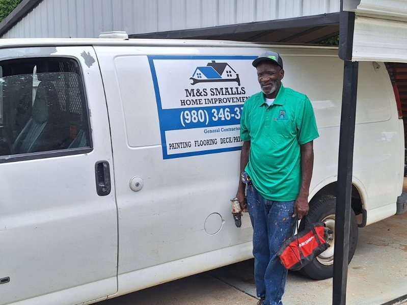 Man in green shirt standing next to a white service van with a business logo.