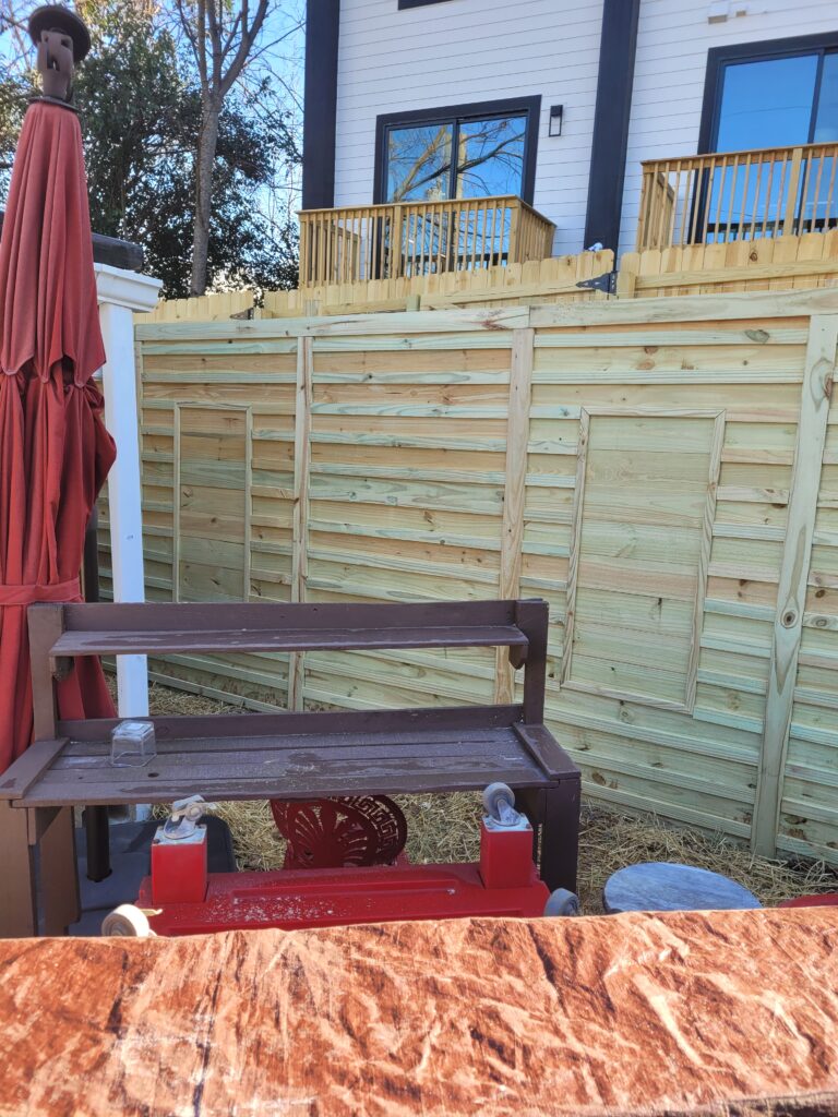 Wooden bench and table in a backyard with a wooden fence.