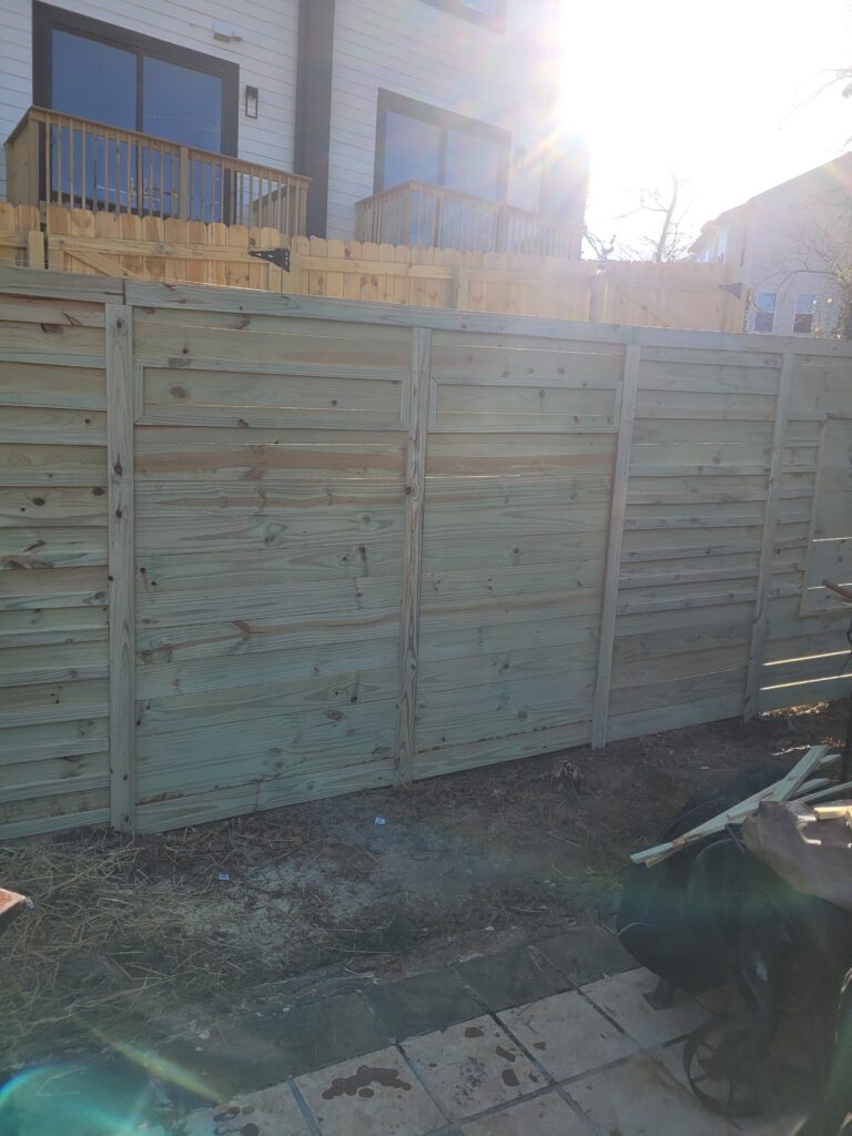 Wooden fence panels installed outdoors under bright sunlight.