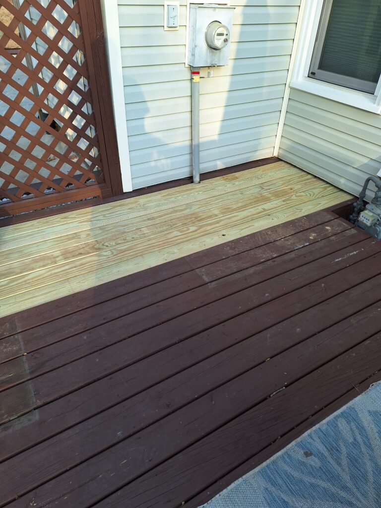 A wooden deck with new planks replacing old ones, showing color contrast.