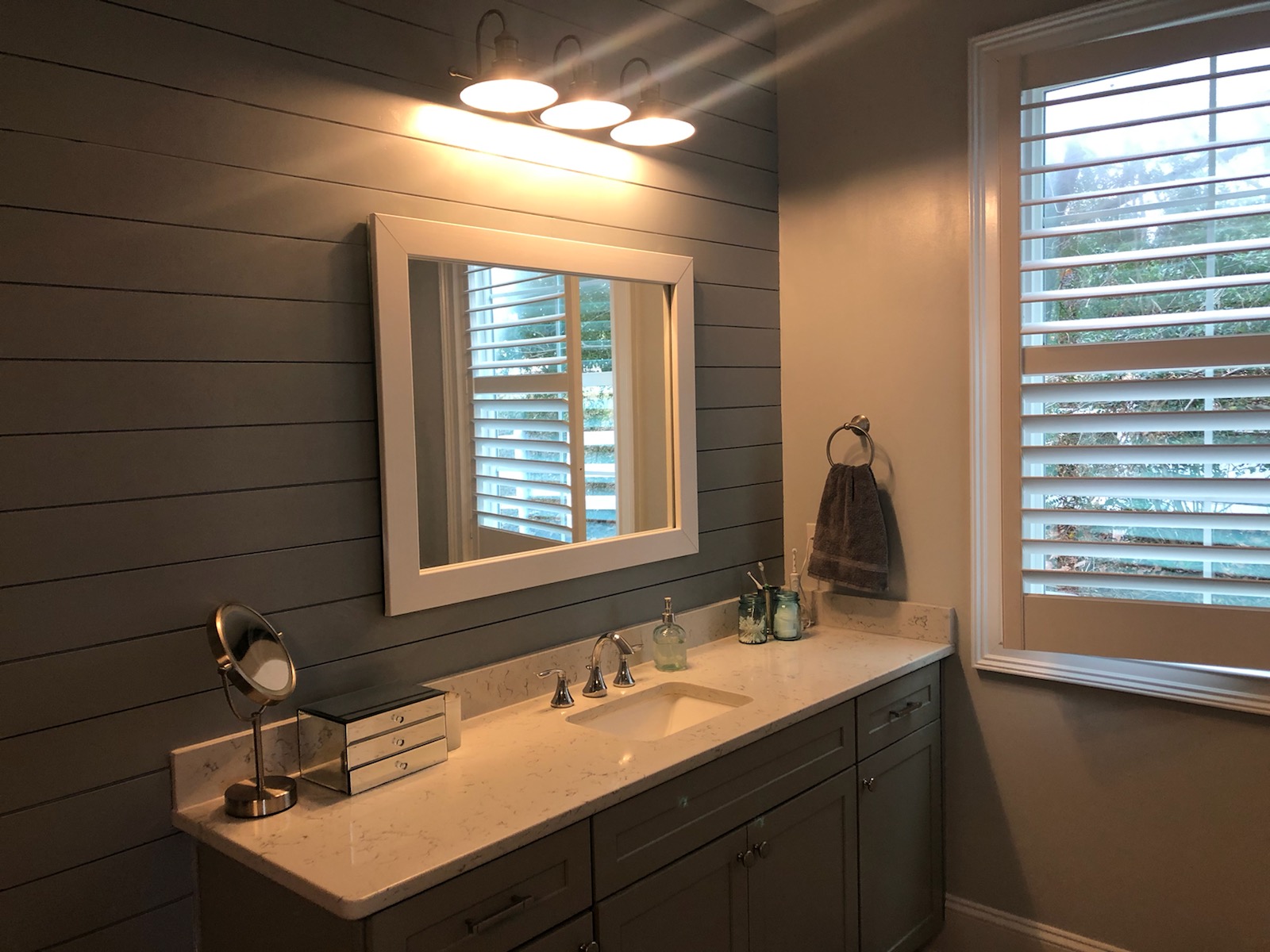Modern bathroom vanity with large mirror and overhead lighting.