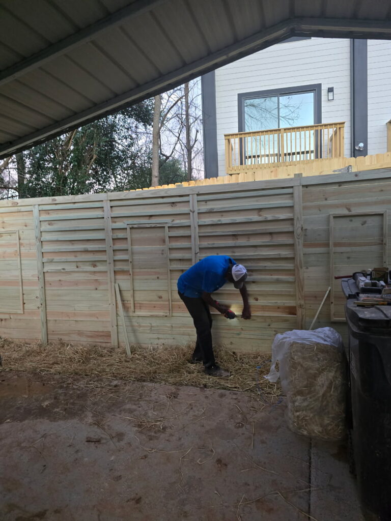 Worker building a wooden fence on a construction site.